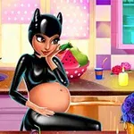 Siyah deri kıyafet giymiş hamile bir kadın, mutfakta otururken arka planda meyve ve mumlar ile renkli dekorasyonlar görülüyor
