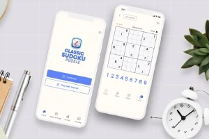 İki beyaz akıllı telefon ekranında sudoku oyununun ana menüsü ve bir sudoku bulmacası, yanında bitki, kalem, defter ve beyaz masa saati