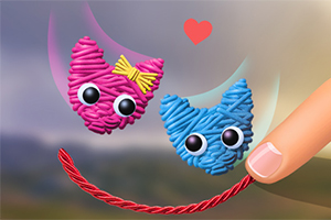 Örgü şeklinde pembe ve mavi kedi figürlerinin yanında, pembe bir kalp ve bir parmakla tutulan kırmızı bir ip gösterilmektedir