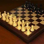 Ahşap bir zemin üzerinde yerleştirilmiş, siyah ve beyaz taşlarla dolu satranç tahtası