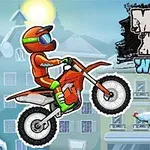 Karlı bir manzarada, kask ve turuncu tulum giymiş bir motosiklet sürücüsü, hava yaparken; yanında süslenmiş bir çam ağacı ve MOTO X3M WINTER yazısı bulunuyor
