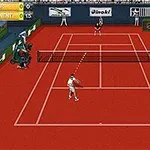 Kırmızı toprak zeminde oynanan bir tenis maçında iki oyuncu, ortada file ile karşılıklı dururken, etrafta seyirciler ve skor tabelaları bulunuyor