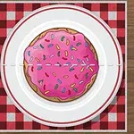 Pembe kremalı ve renkli şekerlemeli kurabiye, kırmızı ekoseli kare masa örtüsünün üzerine konmuş, beyaz bir tabakta sunulmuş; etrafında çatal ve bıçak bulunmakta