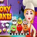 Bir aşçı şapkalı kadın, çeşitli sevimli ve korkunç tasarımlarla süslenmiş altı adet cupcake tepsisi tutuyor