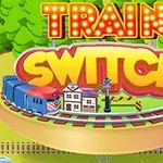 Yuvarlak bir platform üzerinde tren, küçük bir istasyon binası ve tabelalar ile çevresinde TRAIN SWITCH yazan renkli grafikler