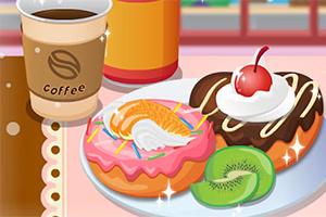 Bir fincan kahve, pembe kremalı ve meyvelerle süslenmiş iki donut ile kivi dilimleri bir tabakta
