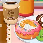 Bir fincan kahve, pembe kremalı ve meyvelerle süslenmiş iki donut ile kivi dilimleri bir tabakta